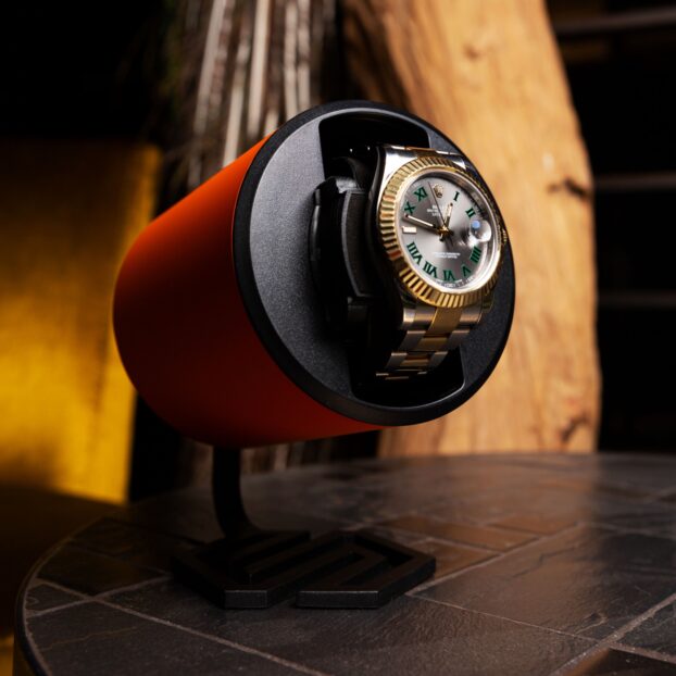 Swiss Capsule single watch winder in Orange set on a stone table winding a Rolex Datejust